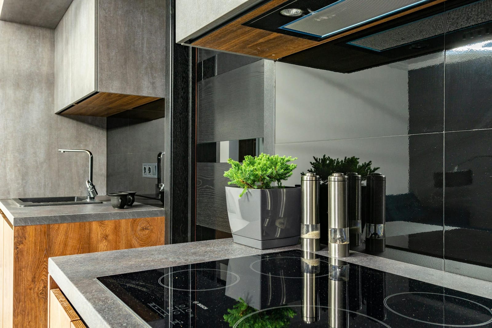 Black induction cooktop set into a kitchen bench with a stainless steel range hood above