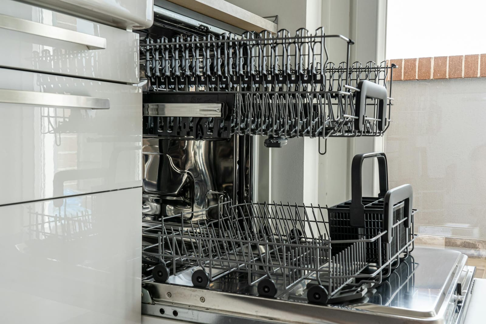 Newly installed dishwasher with door open beside an exposed brick kitchen wall