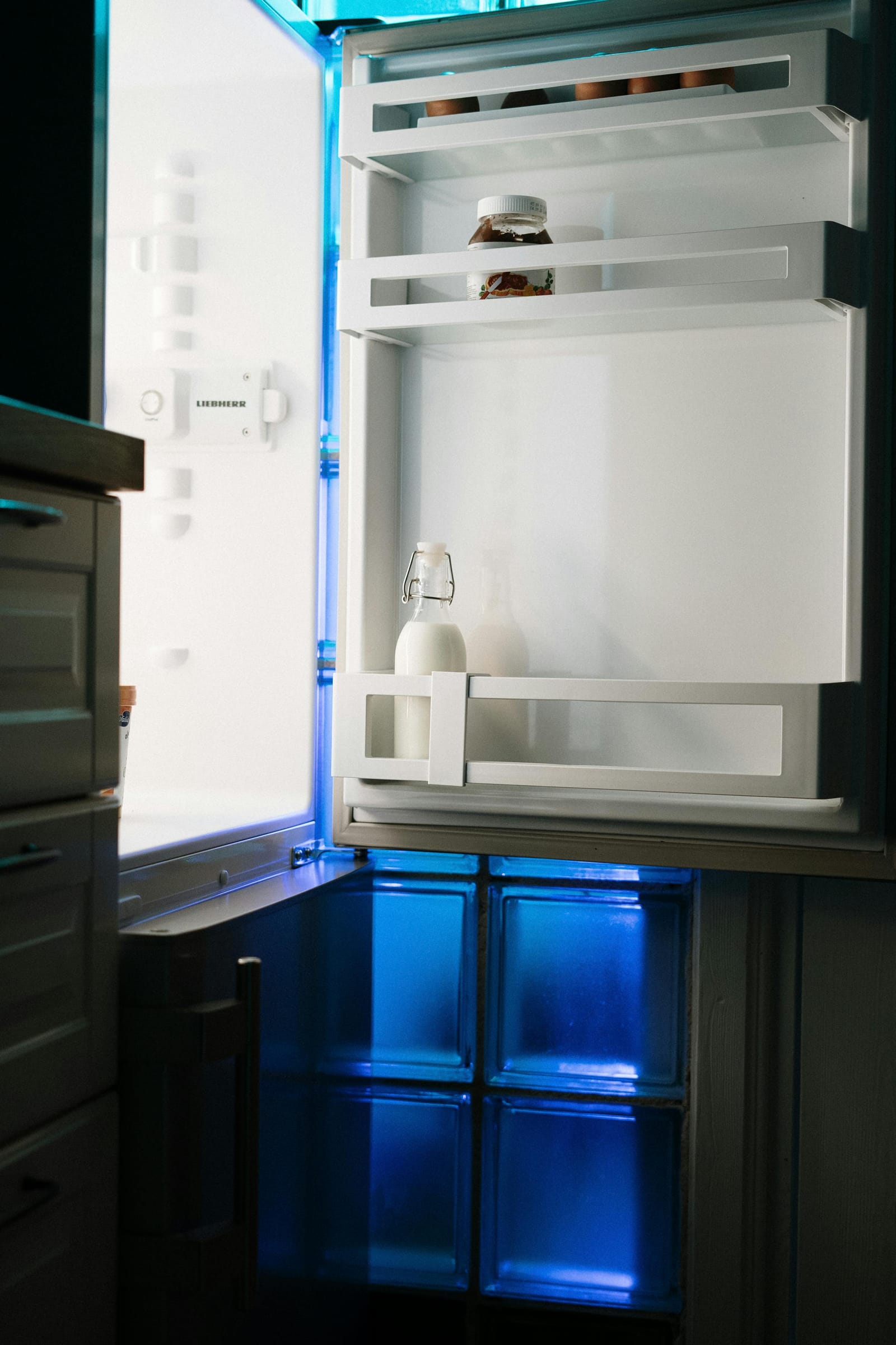 Open Liebherr fridge-freezer with blue-lit freezer compartment visible below