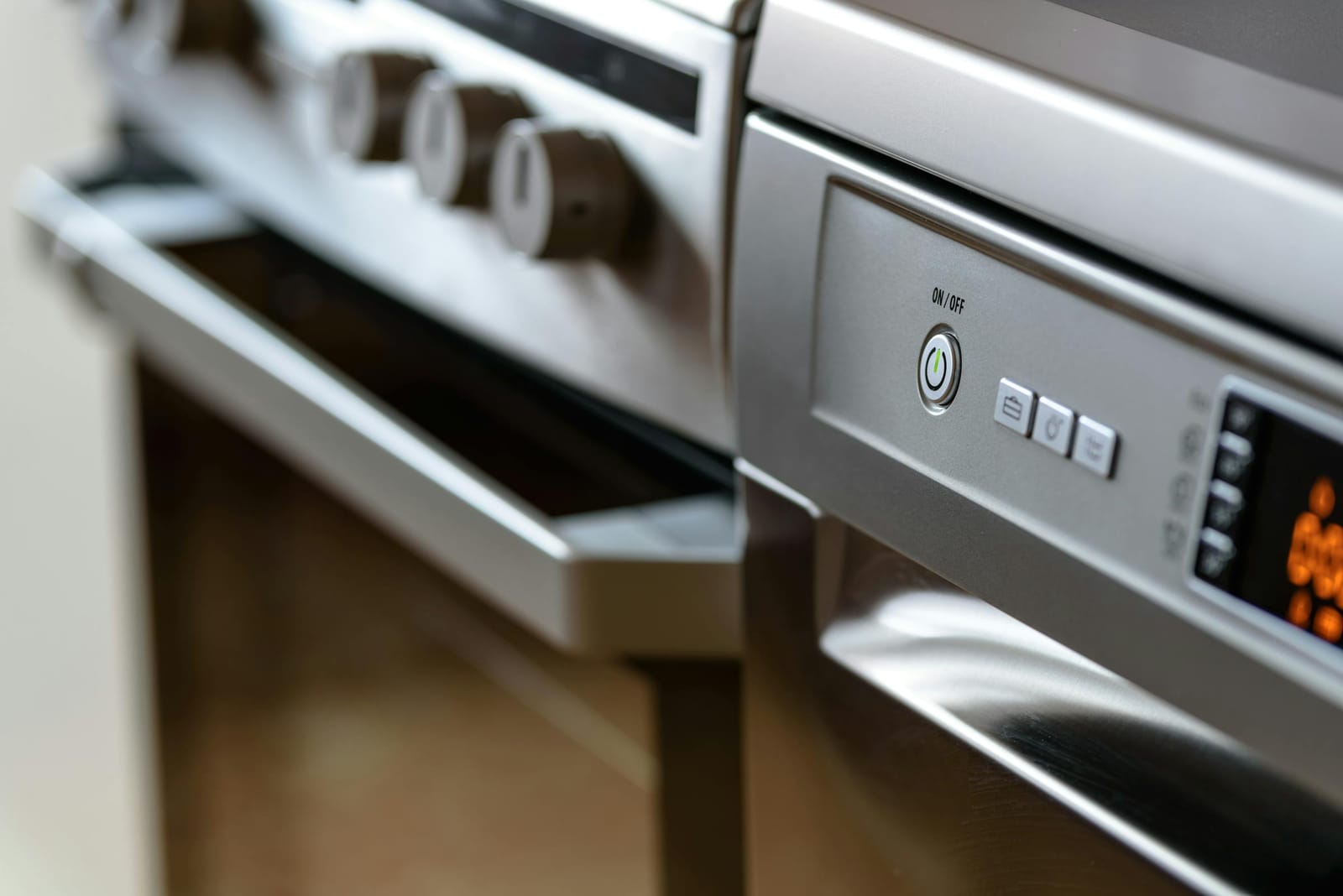 Close-up of a stainless steel oven control panel with chrome knobs