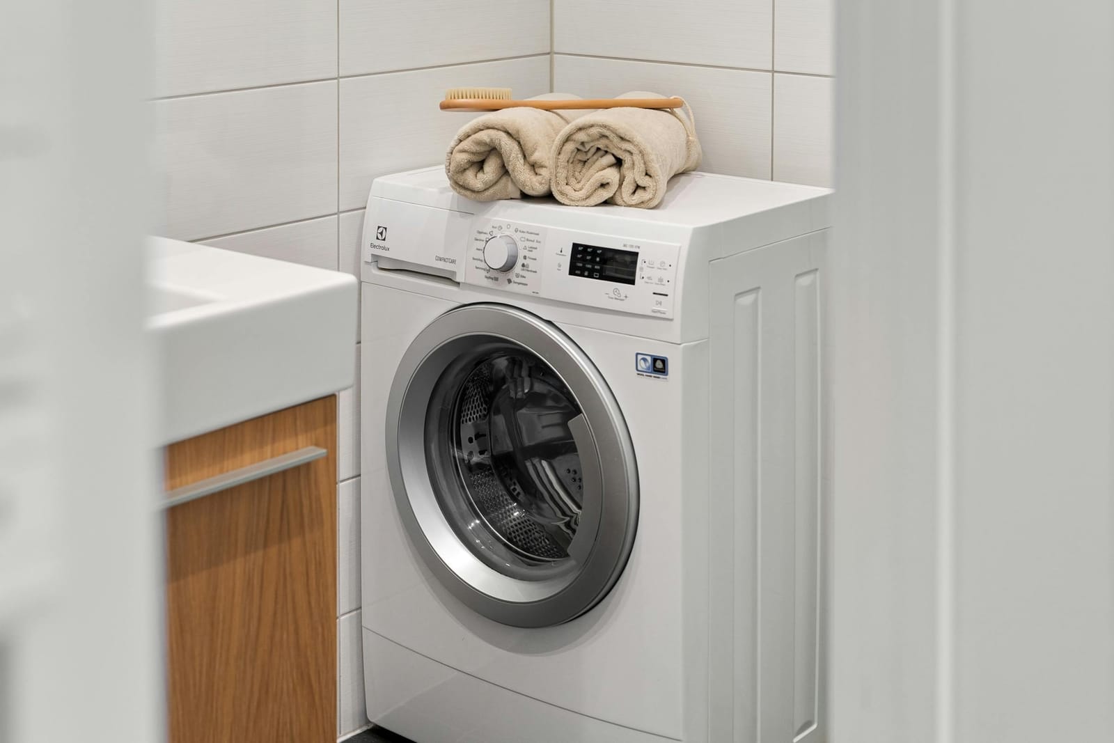 Front-loader washing machine in a tidy Sydney laundry with neatly folded towels on top